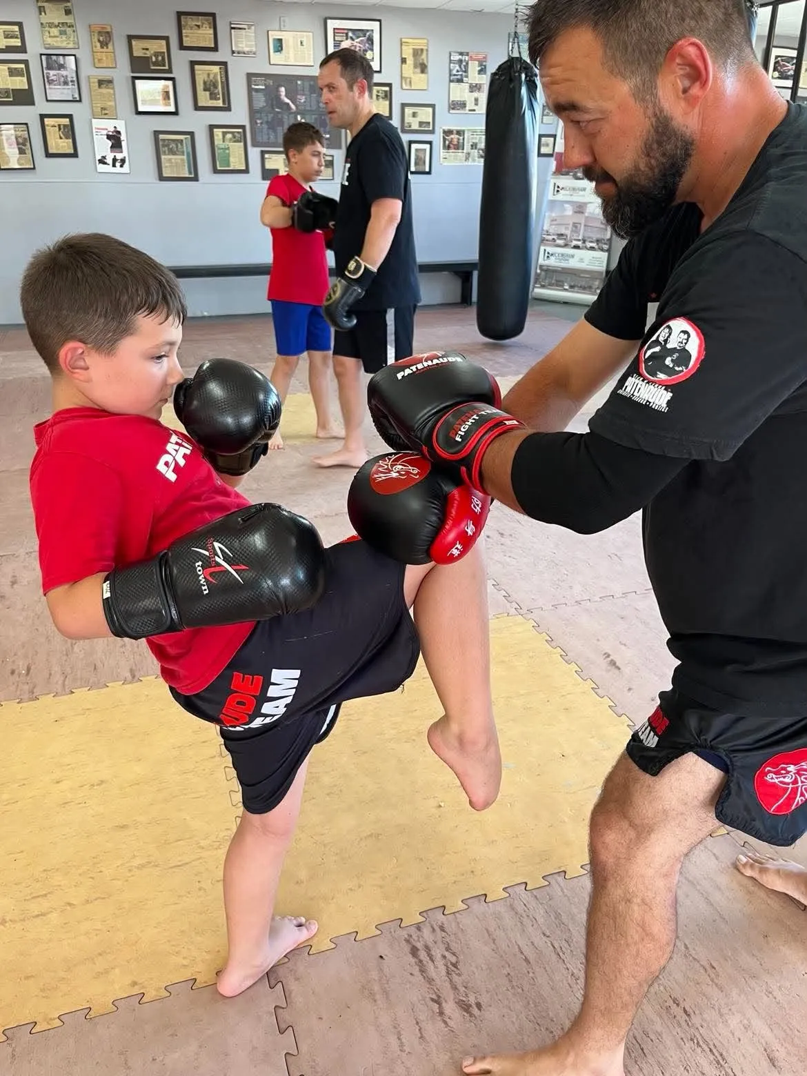 Un jeune travaille son genou sur les gants que lui tient un instructeur